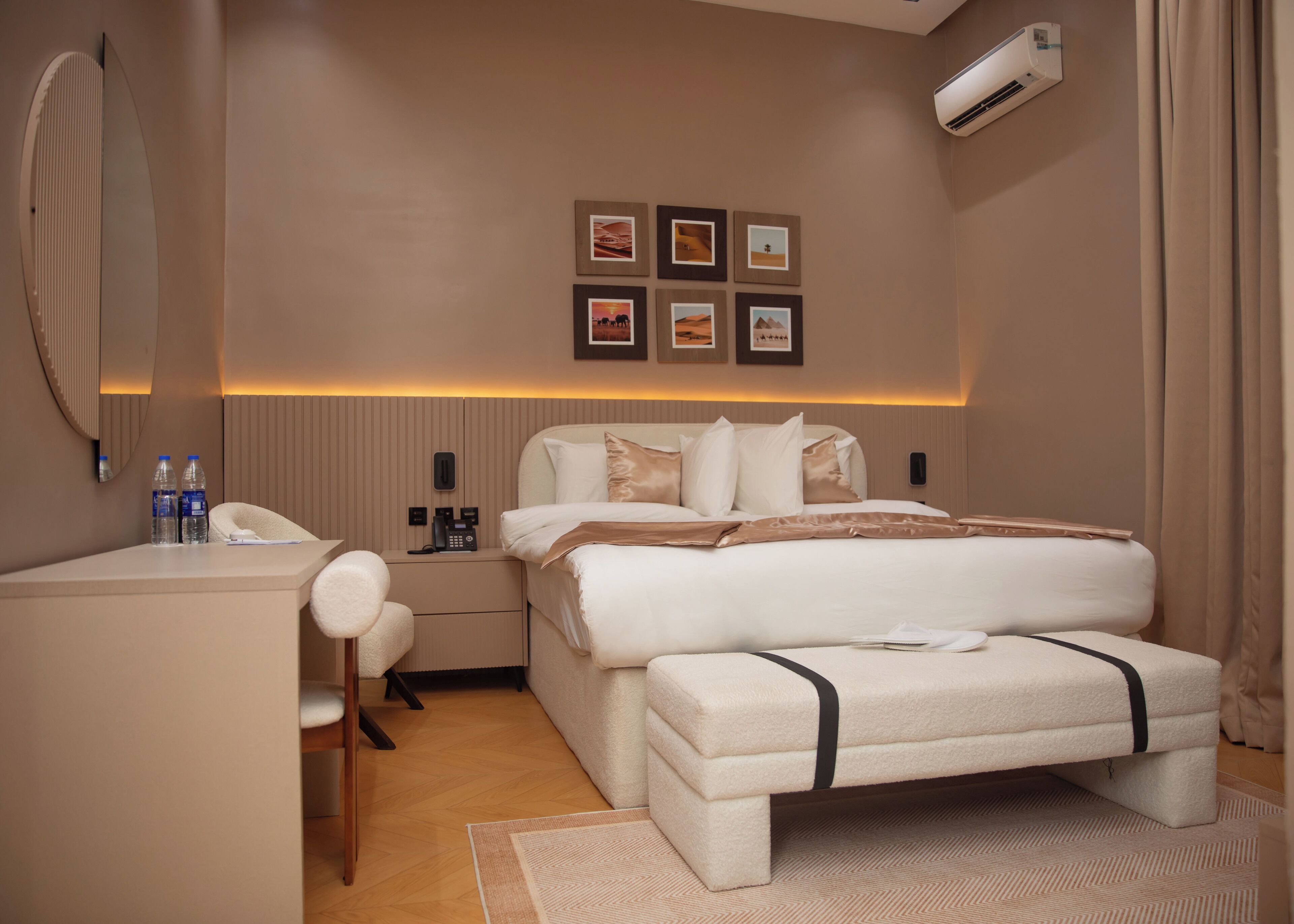 A hotel room with a bed, bedside table, chair, and wall-mounted air conditioning unit.