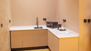Une cuisine moderne avec un plan de travail blanc, un évier et un four à micro-ondes.