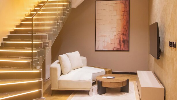 Un intérieur moderne avec un escalier, un canapé, une table basse et un téléviseur à écran plat fixé au mur.