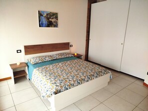 Une chambre à coucher comprenant un lit, une table de chevet, un tableau accroché au mur et une armoire.