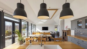Cozinha moderna com uma ilha grande, iluminação pendente e vista para o exterior.