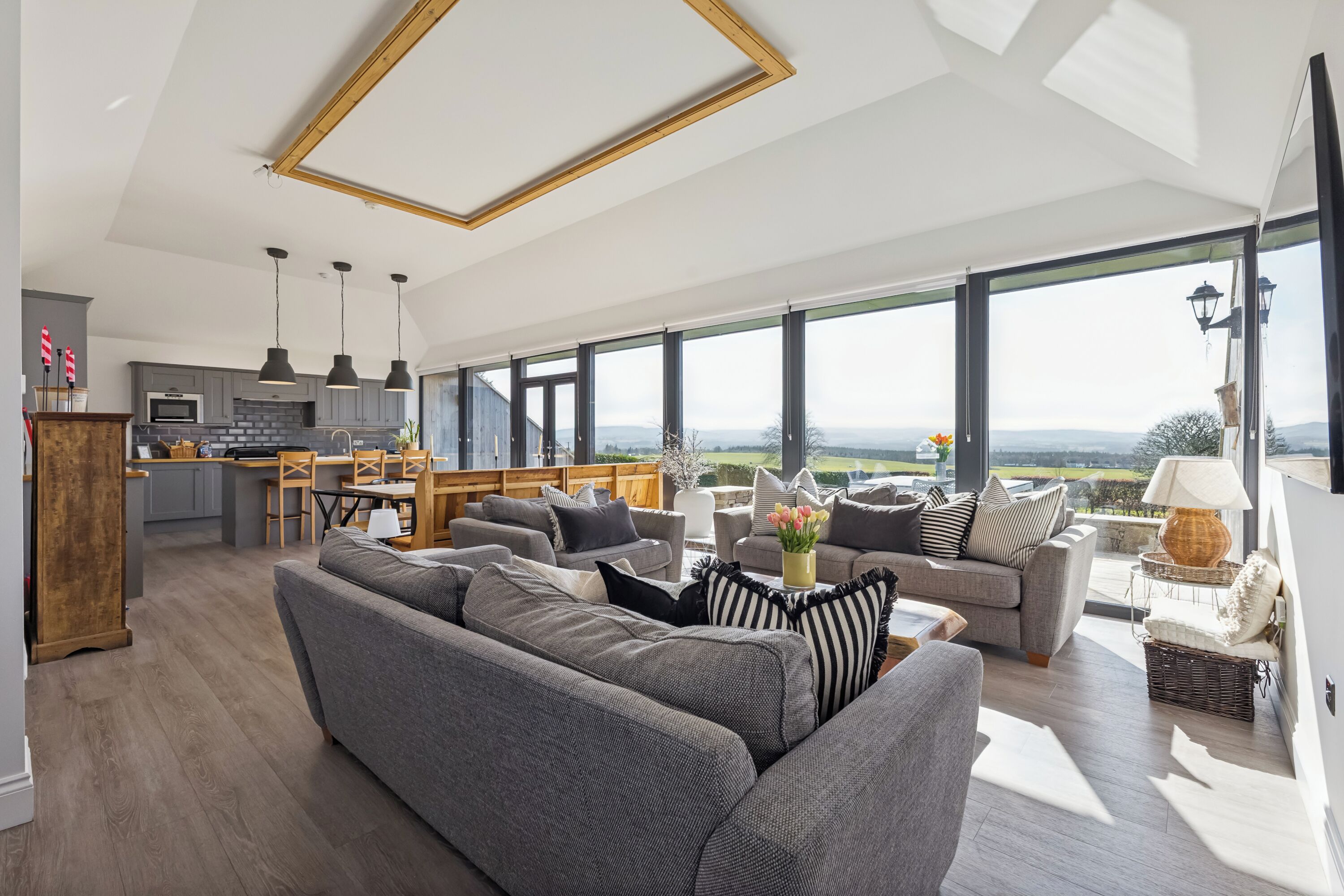 Amplia sala de estar con un sofá grande, una mesa de comedor y una cocina al fondo.
