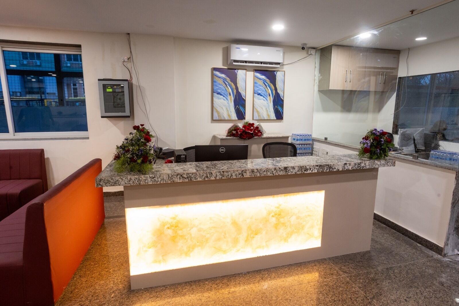 A reception desk with a marble top, a glass partition, and a large illuminated panel.