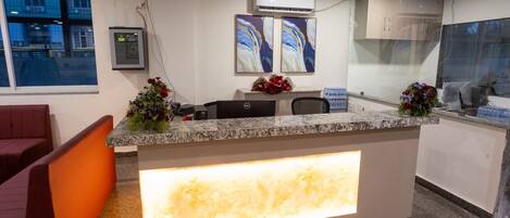 A reception desk with a marble top, a glass partition, and a large illuminated panel.
