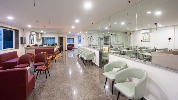 A modern hotel lobby with a reception desk, seating area, and a large mirror wall. - Hotel V Grand (Hyderabad)