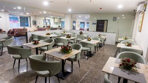 A restaurant with multiple tables and chairs, arranged in a spacious layout. - Hotel V Grand (Hyderabad)