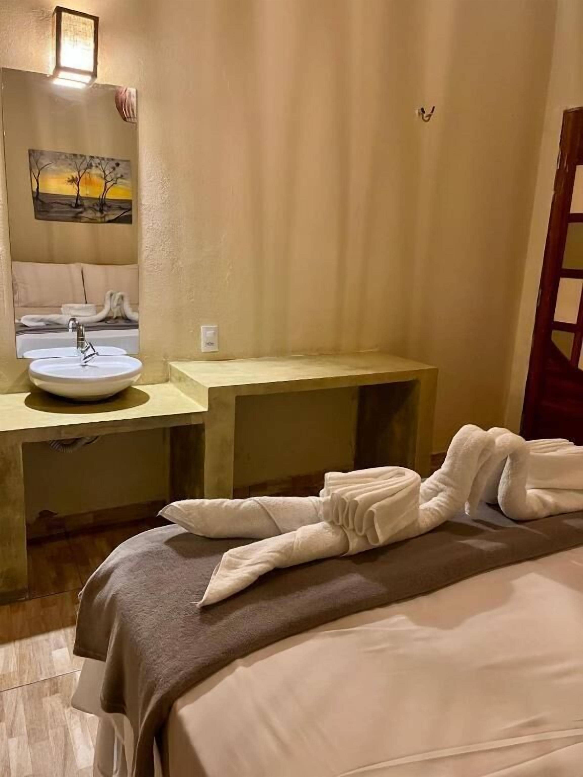 Une chambre d’hôtel avec un lit, un lavabo et un tableau au mur.