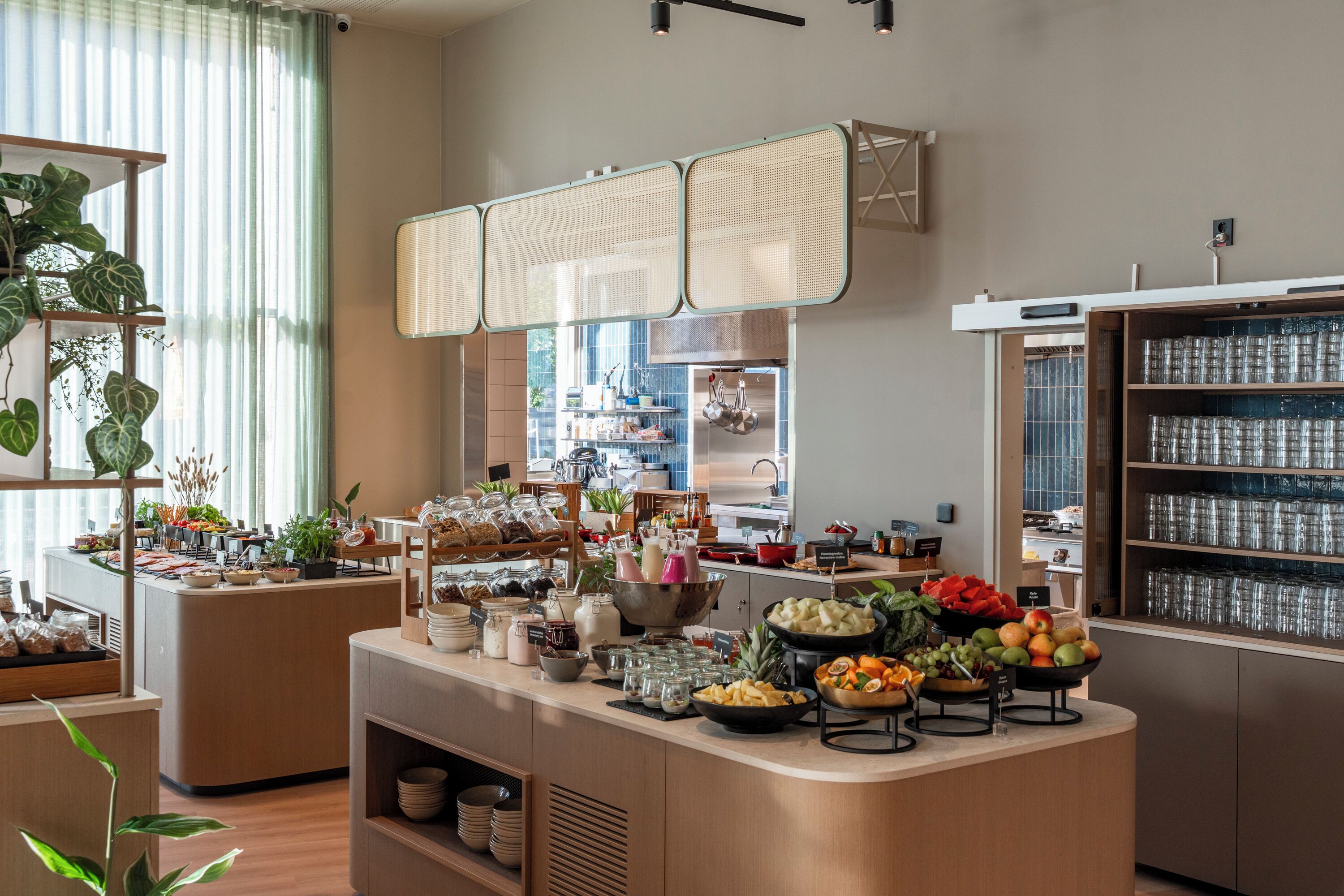 Zona de bufé con diferentes opciones de comida y una cocina al fondo.