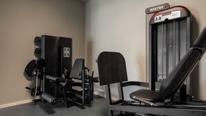 Un gimnasio con una máquina de prensa de piernas, una torre de pesas y un banco.