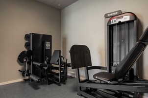 A gym with a seated leg press machine, a weight stack, and a bench.