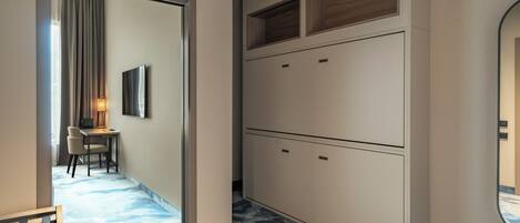 A hotel room with a desk, chair, and a large wardrobe with multiple doors.