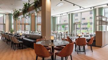 A spacious restaurant with high ceilings, large windows, and a variety of seating options including tables and booths.