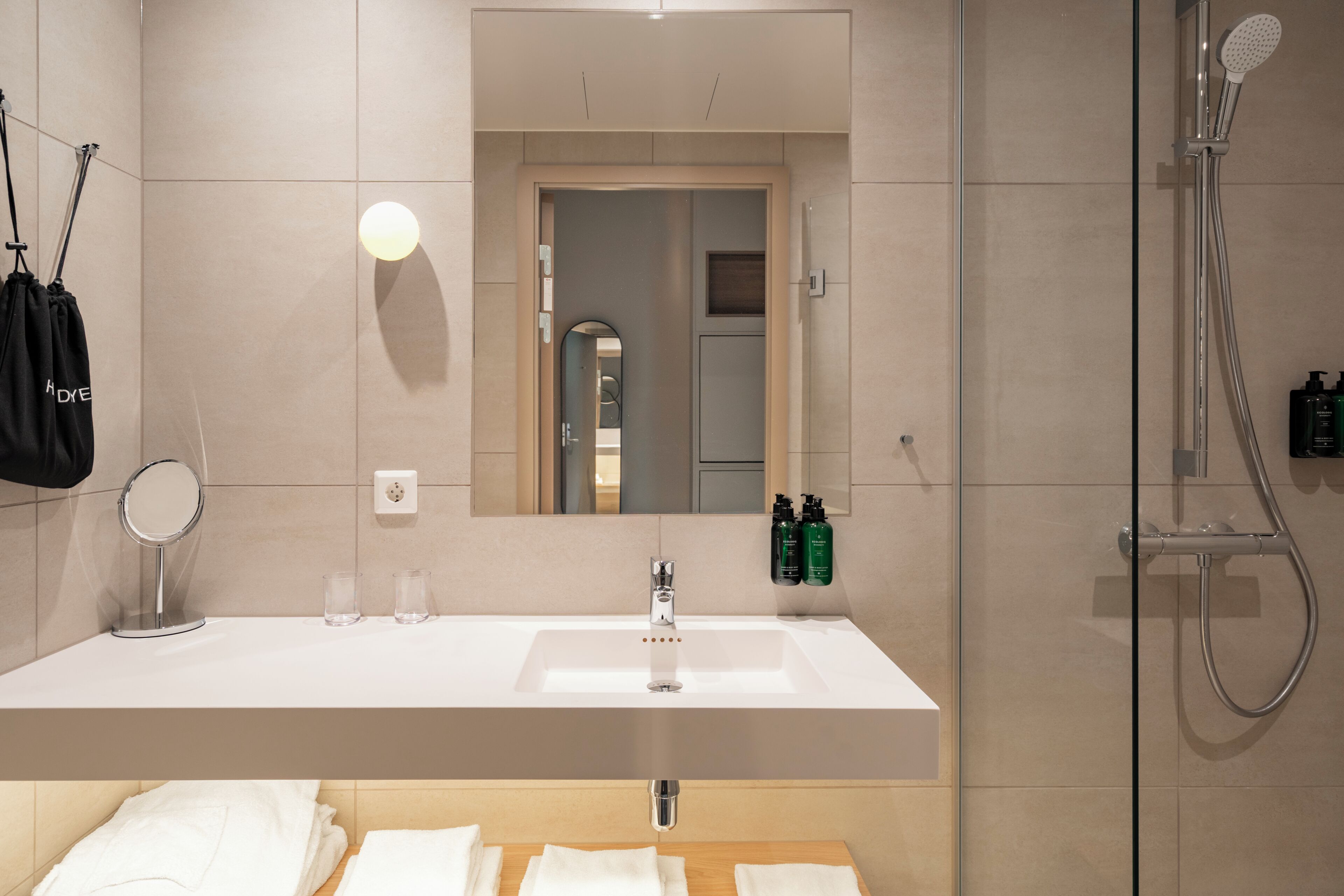 A modern bathroom with a large mirror, a sink, and a shower.