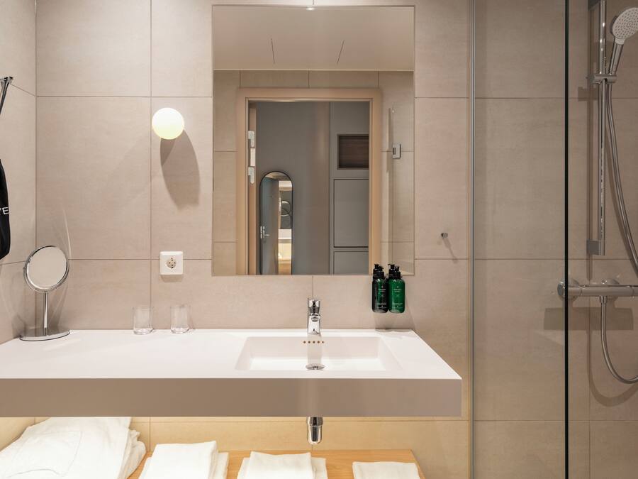 A modern bathroom with a large mirror, a sink, and a shower.