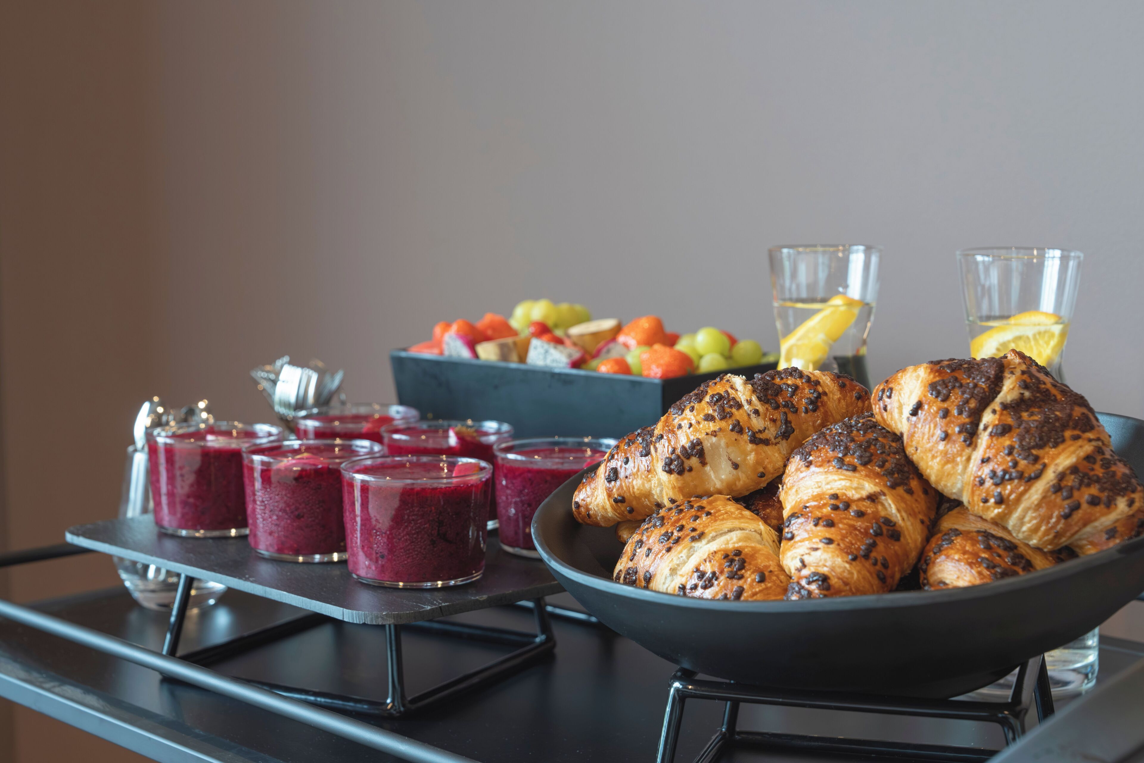 Un bufé de desayuno con croissants, fruta y batidos.