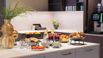 Et moderne køkken med et buffetbord, der indeholder frugt, kager og drikkevarer.