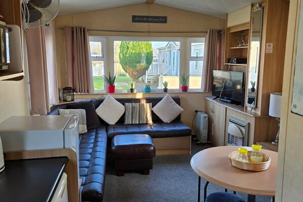 Ein kompakter Wohnbereich mit Sofa, Hocker und einem kleinen Tisch mit Flaschen.