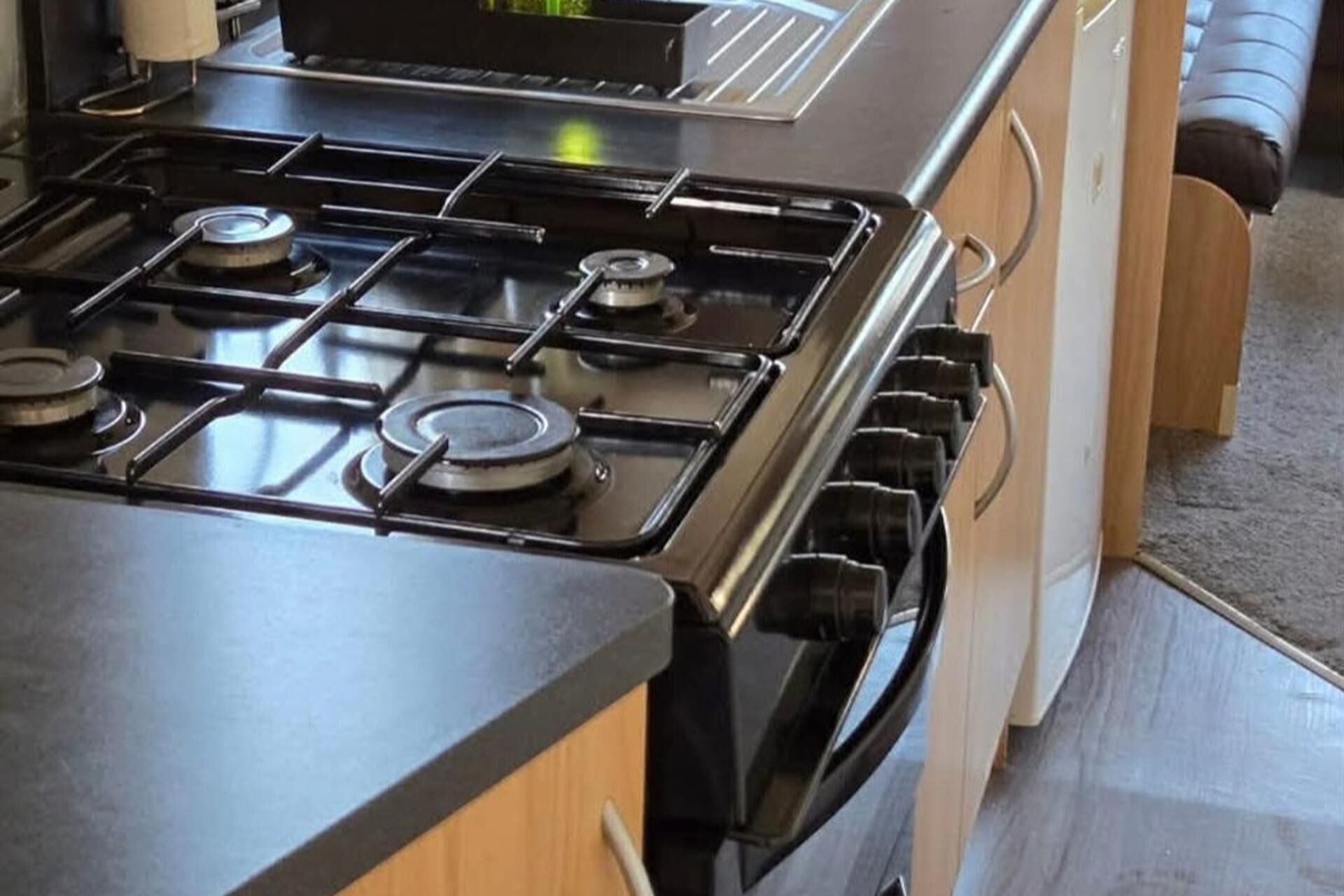 Une cuisine équipée d’une cuisinière, d’un four et de meubles de rangement en bois.