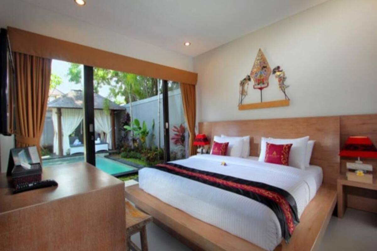 A hotel room with a large bed, a desk, and a view of a garden.