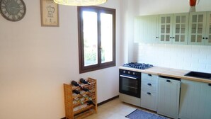 A kitchen with a gas stove, oven, wine rack, and light-colored cabinets. - Casa Florian (Vito d'Asio)