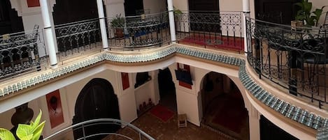 A multi-level courtyard with balconies, arches, and a hanging planter.