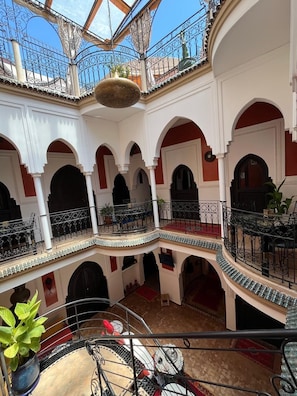 Un patio de varios niveles con balcones, arcos y un jardín colgante.