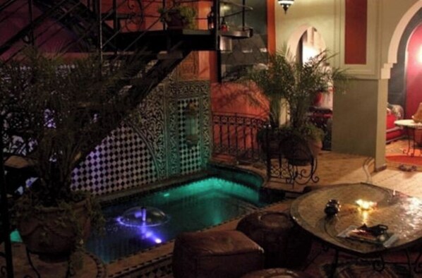 Un área de piscina interior con una escalera de caracol, asientos y una pequeña mesa con una vela.