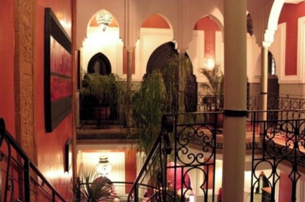 Un hall d’hôtel avec un escalier, des plafonds en arc de cercle et une fontaine.