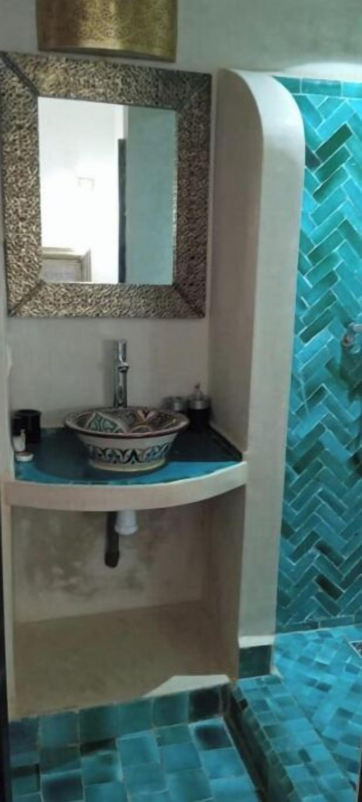 Un baño con lavamanos, espejo y azulejos estampados.