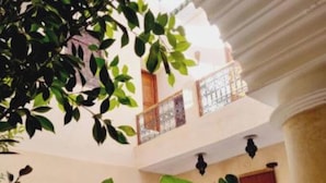 A spacious interior with a high ceiling, multiple arches, and a variety of potted plants. - Riad Kantarell (Marrakech)