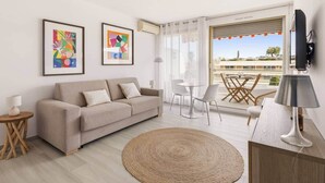 Una sala de estar moderna con un sofá, un tapete redondo, una mesa de comedor con sillas y obras de arte en las paredes.