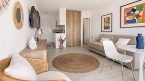 Una sala de estar moderna con un sofá, sillas, una mesa de centro, un televisor y obras de arte en las paredes.