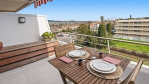 Un balcón con mesa de madera para dos, una banca y vistas de la ciudad.