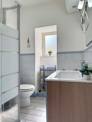 A bathroom with a toilet, a sink, a window, and a shower area. - [5 Min from the Duomo] Quiet & Central Apartment • Historic Center of Catania (Catania)