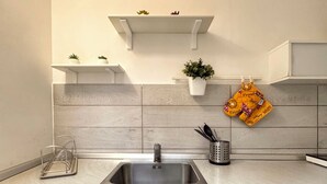 Eine Küche mit Spüle, blauen Schränken, einer weißen Spritzschutzwand und einem an der Decke befestigten Topfhalter mit Pflanzen.