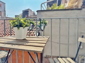 A rooftop terrace with a potted plant, metal railing, and a view of buildings in the background. - [5 Min from the Duomo] Quiet & Central Apartment • Historic Center of Catania (Catania)
