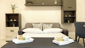 Ein modernes Hotelzimmer mit einem Bett, zwei Nachttischen, einem Sessel und integrierten Regalen mit Dekoration.