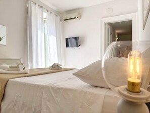 A hotel room with a bed, a television, an air conditioning unit, and a lamp. - [5 Min from the Duomo] Quiet & Central Apartment • Historic Center of Catania (Catania)