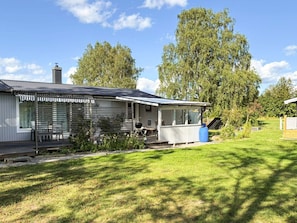 A single-story house with a porch, a chimney, and a yard with grass and trees.
