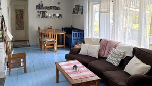 A cozy living room with a brown sofa, a wooden coffee table, and a dining area with a wooden table and chairs. - 4 Star Holiday Home in Sorunda (Sorunda)