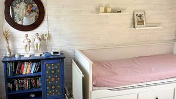 A bedroom with a white bed, a blue bookshelf, a mirror, and a wall clock.