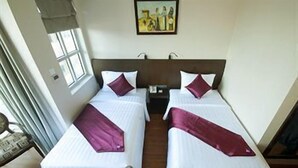 Hotellihuone, jossa on kaksi sänkyä, ikkuna, seinällä taulu ja tuoli.