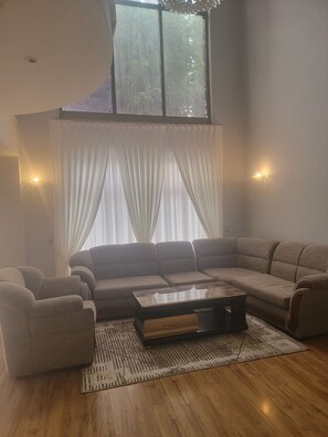 Un salon moderne avec un canapé d’angle, une table basse et un tapis à motifs.