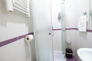 Une salle de bain avec une douche à parois de verre, un lavabo blanc et un porte-serviettes.