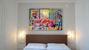 A hotel room with a bed, two wall sconces, and a large abstract painting above the bed. - Lecasinedigiò2 Cozy and refined apartment with sea view terrace (Alghero)