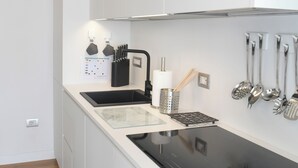 A modern kitchen with white cabinets, a black countertop, and a stainless steel range hood. - Lecasinedigiò2 Cozy and refined apartment with sea view terrace (Alghero)