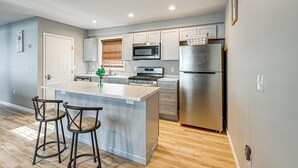 A modern kitchen with a central island, stainless steel appliances, and bar stools. - Walkable Stay Near Hudson River, Dining & Shopping (Hudson)