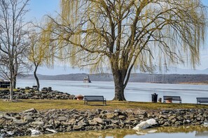 A lakeside park with benches, a large tree, and a distant lighthouse. - Walkable Stay Near Hudson River, Dining & Shopping (Hudson)