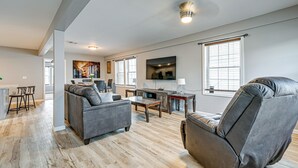 A modern living room with a sofa, a recliner, a coffee table, and a TV. - Walkable Stay Near Hudson River, Dining & Shopping (Hudson)