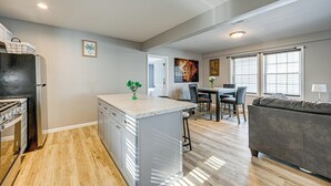 A modern kitchen with a central island, a dining area with a table and chairs, and a living area with a couch. - Walkable Stay Near Hudson River, Dining & Shopping (Hudson)